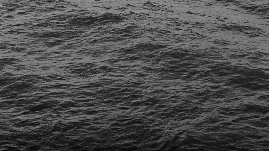 Photo en noir et blanc de l'océan, vue sur l'eau et ses ondes uniquement.