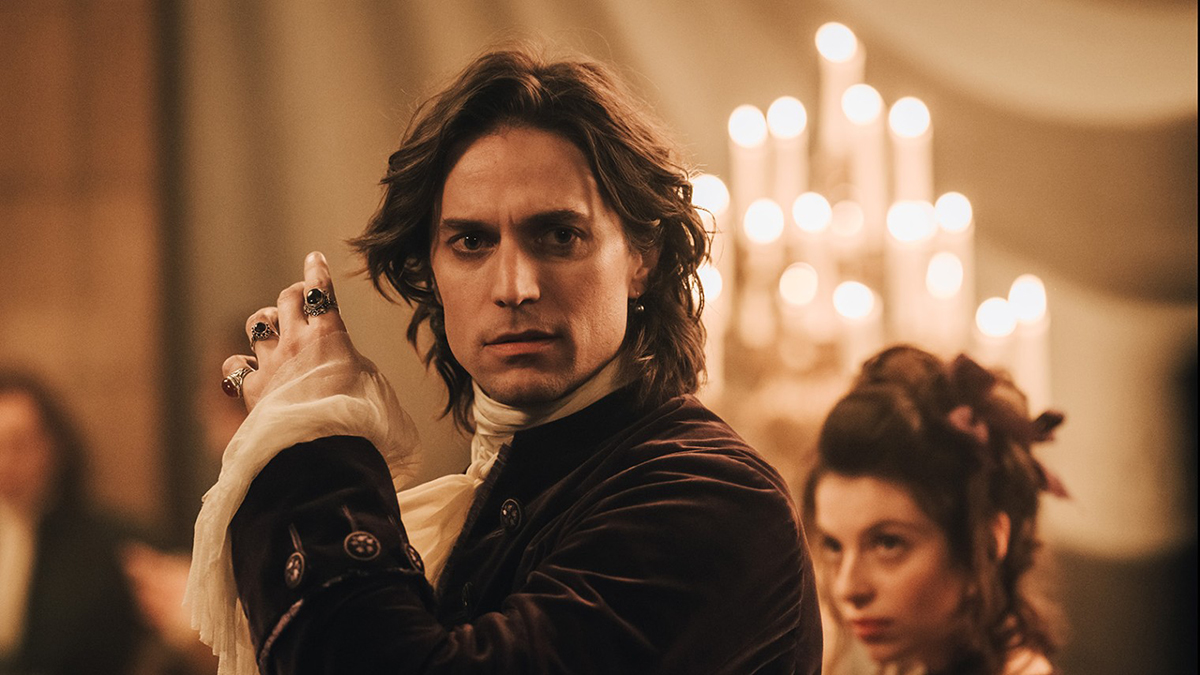 Lucas Bravo, loubard trentenaire du dix-huitième siècle, avec ses cheveux longs, son khôl dans les yeux, ses bagouzes à chaque doigt et sa chemise à jabot.