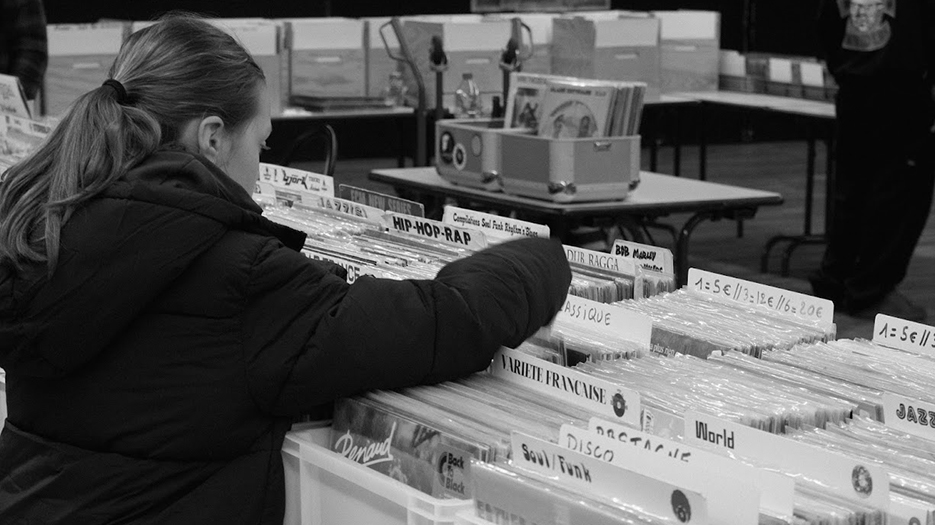 Une petite fille en train de fouiller des bacs à vinyles.