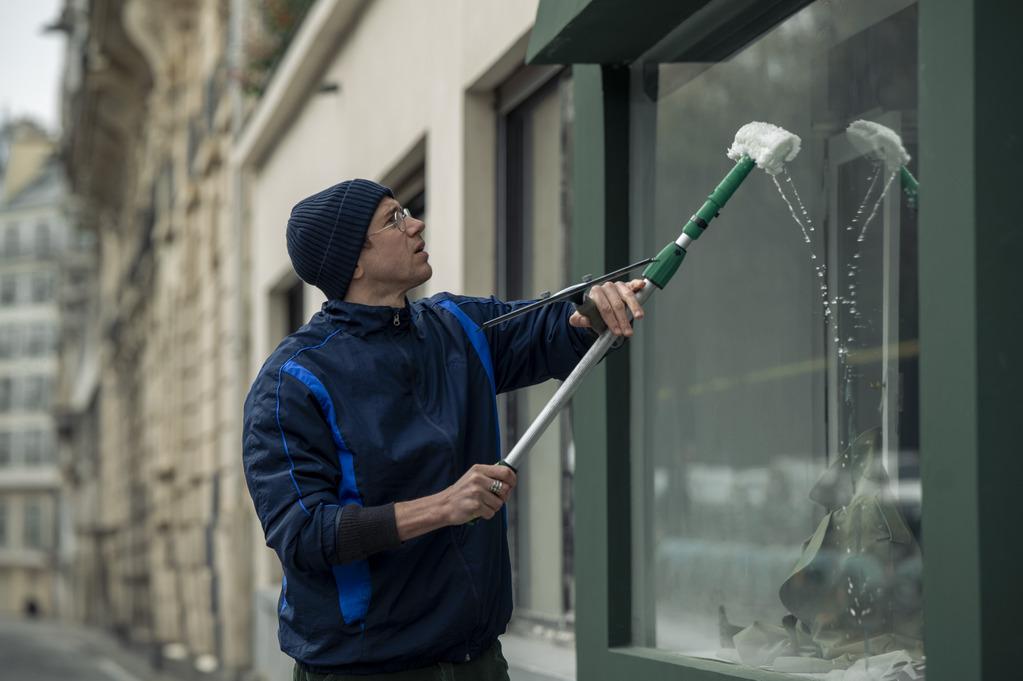 Bastien Bouillon en train de laver la vitrine d'une boutique.